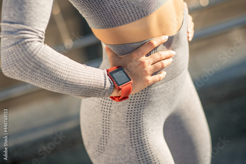 Fototapeta Naklejka Na Ścianę i Meble -  Close up picture of a female in grey sportswear and with a smartwatch on her wrist