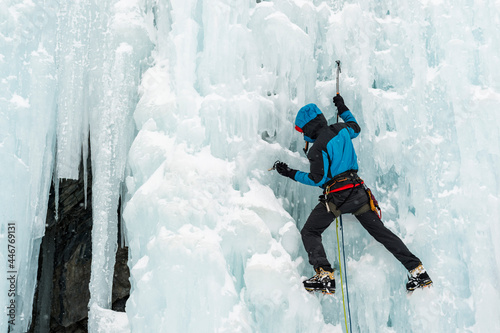 climber making his way down a frozen waterfall