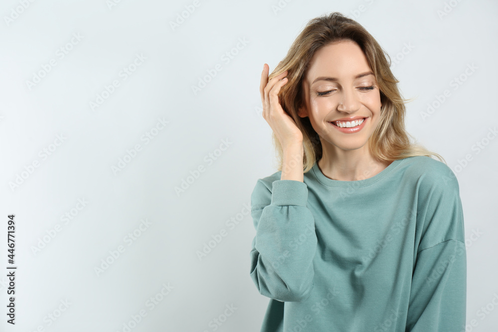 Portrait of happy young woman with beautiful blonde hair and charming smile on light background. Space for text Portrait of happy young woman with beautiful blonde hair and charming smile on light background. Space for text