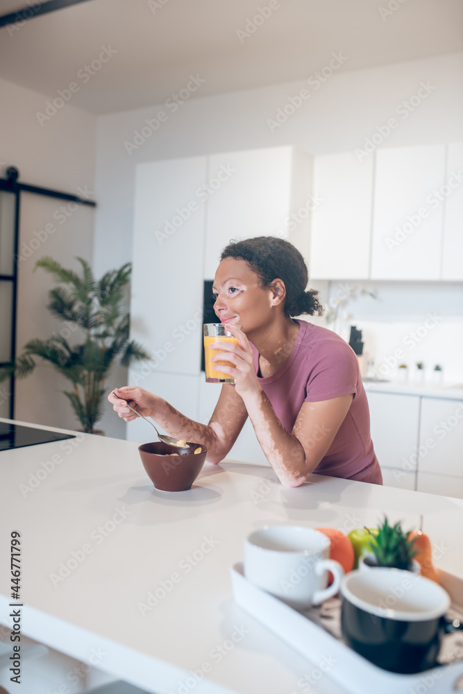 Young dark-skinned woman holding a glass with orange juice Young dark-skinned woman holding a glass with orange juice
