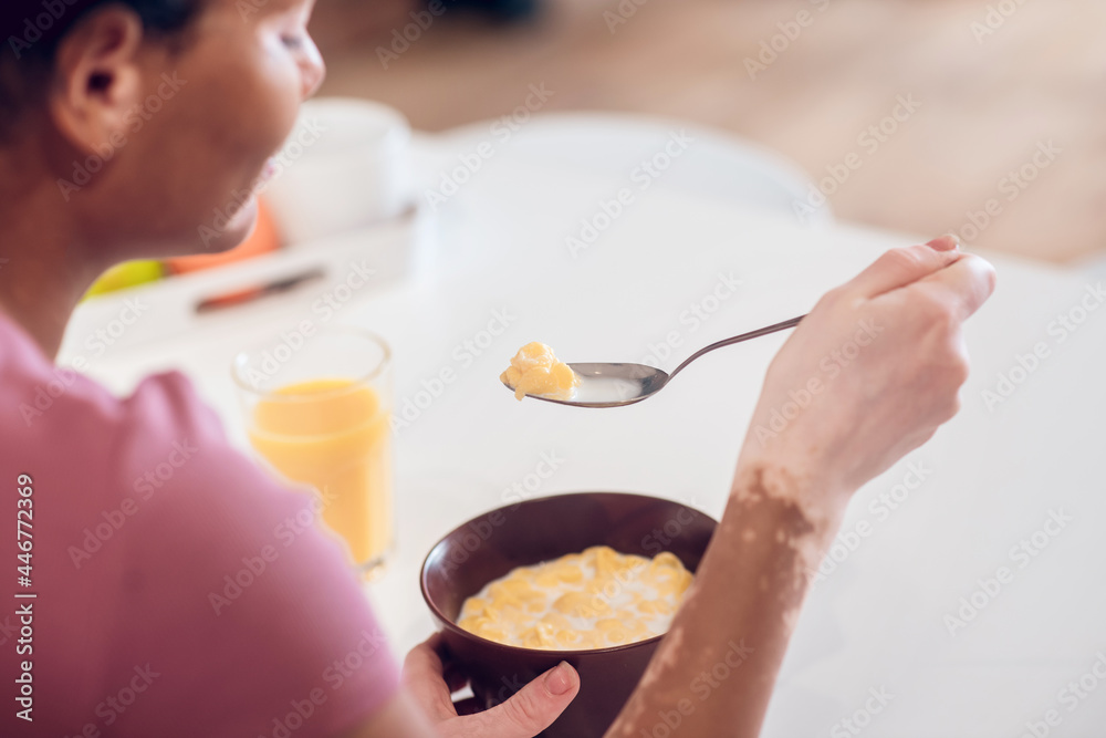 Dark-skinned young woman having breakfast at home