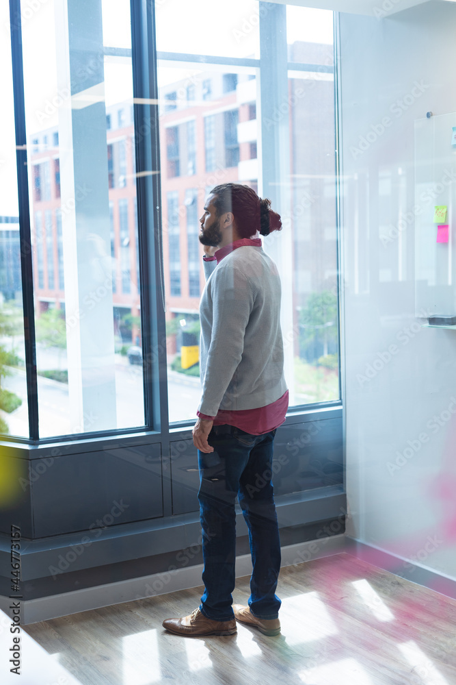 Mixed race male creative worker talking on smartphone standing next to window Mixed race male creative worker talking on smartphone standing next to window