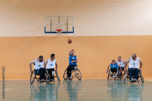 handicapped war veterans in wheelchairs with professional equipment play basketball match in the hall.the concept of sports with disabilities