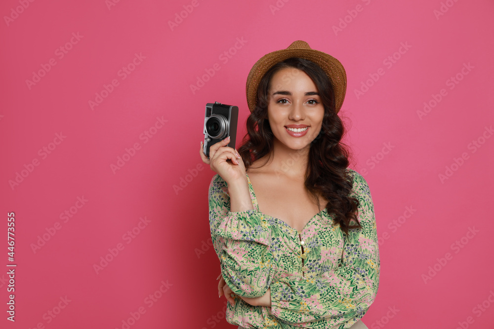 Beautiful young woman with straw hat and camera on pink background. Space for text