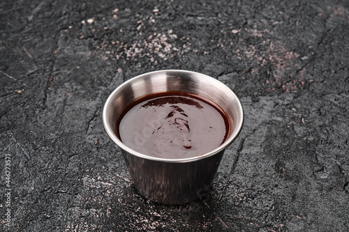 Barbecue sauce in a metal gravy boat isolated on textured black background. Space for text. High quality photo photo