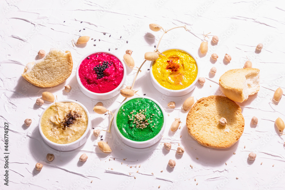 Various hummus dips, the flat lay of hummus in different colors with spinach, beetroot, turmeric and vegetables Various hummus dips, the flat lay of hummus in different colors with spinach, beetroot, turmeric and vegetables
