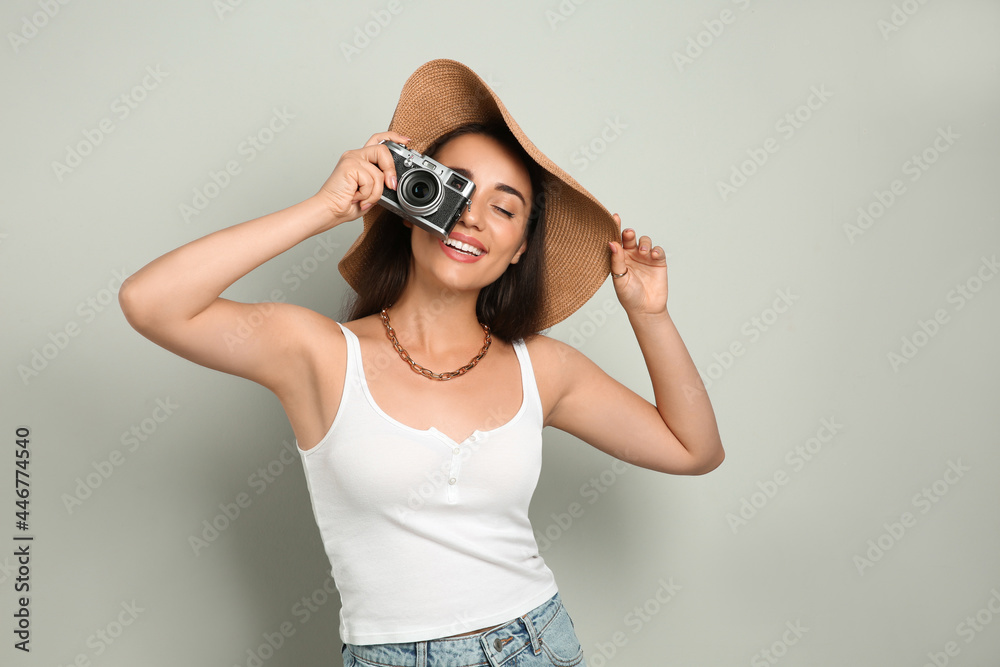 Beautiful young woman with straw hat and camera on light grey background. Stylish headdress Beautiful young woman with straw hat and camera on light grey background. Stylish headdress