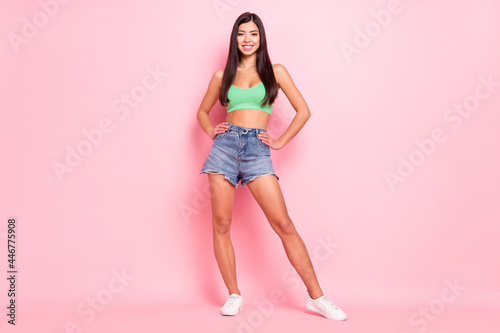 Photo of cute charming young lady wear green tank-top standing arms waist smiling isolated pink color background