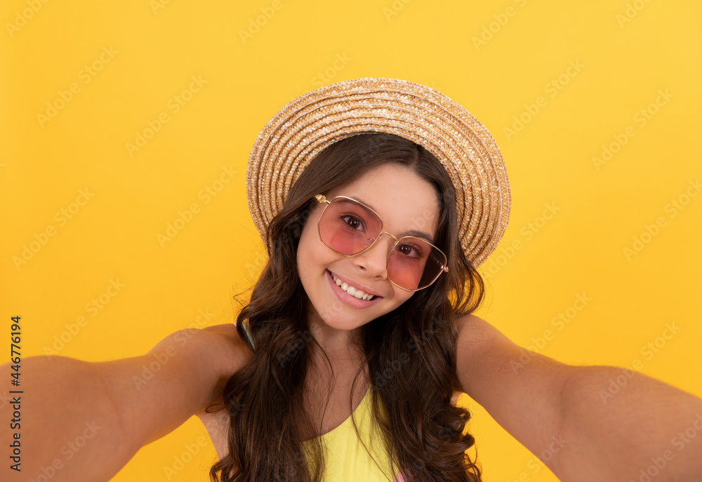happy teen girl in summer straw hat and glasses making selfie on yellow background, childhood happy teen girl in summer straw hat and glasses making selfie on yellow background, childhood