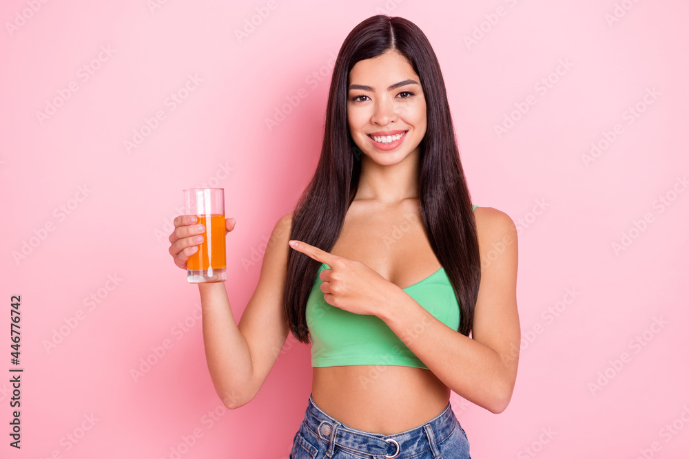 Photo of sweet charming young lady wear green tank-top smiling pointing finger juice glass isolated pink color background Photo of sweet charming young lady wear green tank-top smiling pointing finger juice glass isolated pink color background