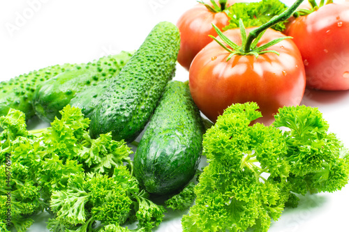 Fresh tomatoes and cucumbers, vegetables and parsley on a white background