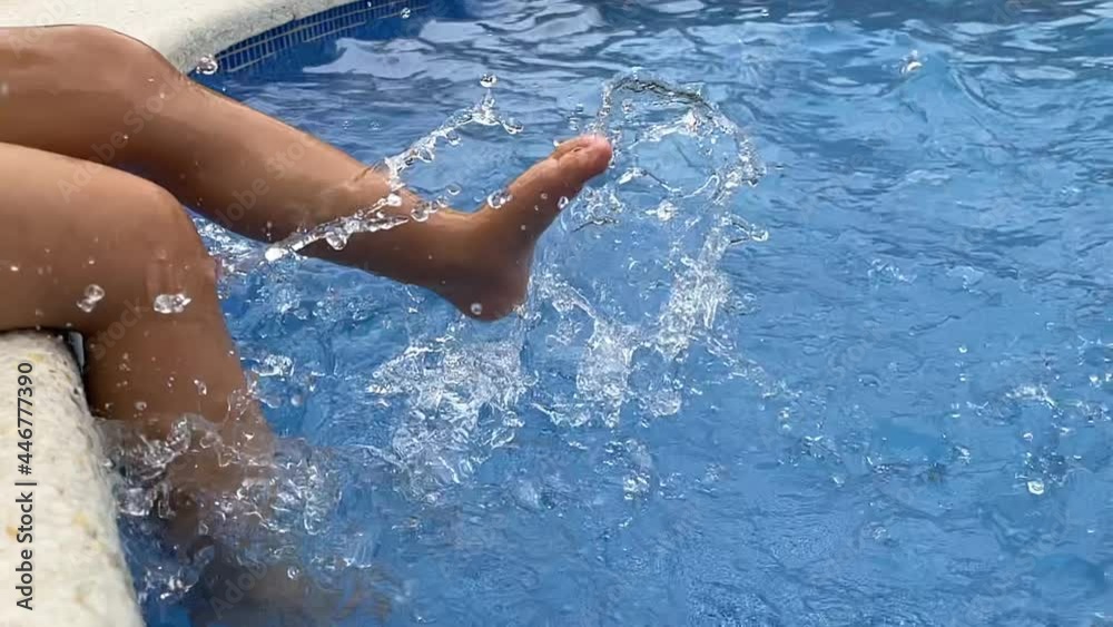 Child splashing feet in swimming pool water Child splashing feet in swimming pool water