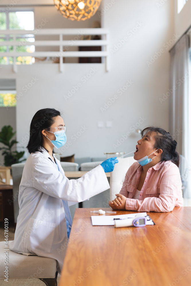 Asian female doctor wearing face mask and taking swab test from female patient at home