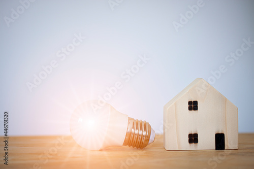 Light bulb with wooden home on table, power energy, save, new idea, new business, mortgage, property, new house and technology innovation.