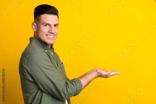 Photo portrait man smiling keeping copyspace on hands isolated vivid yellow color background © deagreez