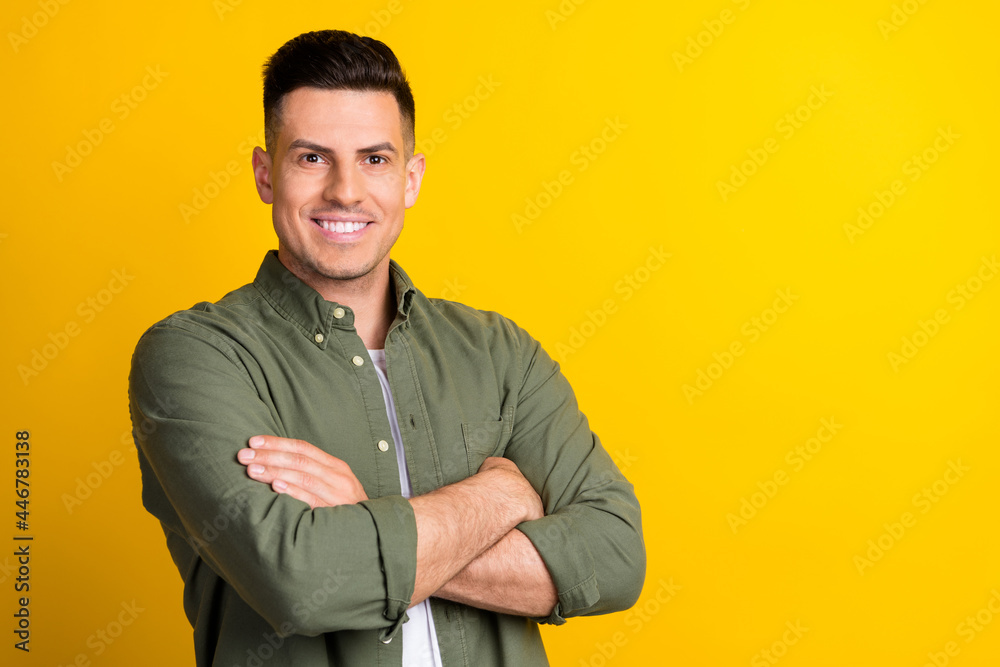 Photo portrait man smiling folded hands in green shirt isolated vivid yellow color background blank space Photo portrait man smiling folded hands in green shirt isolated vivid yellow color background blank space