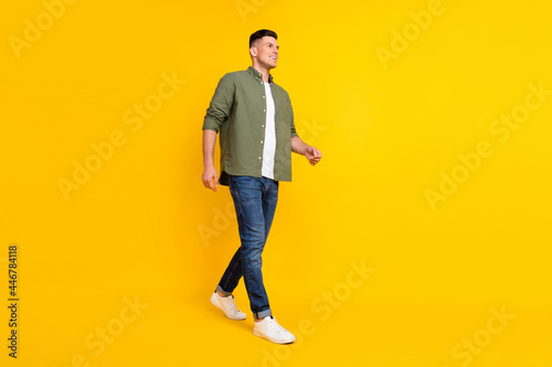 Full length body size photo guy walking forward looking copyspace isolated vibrant yellow color background