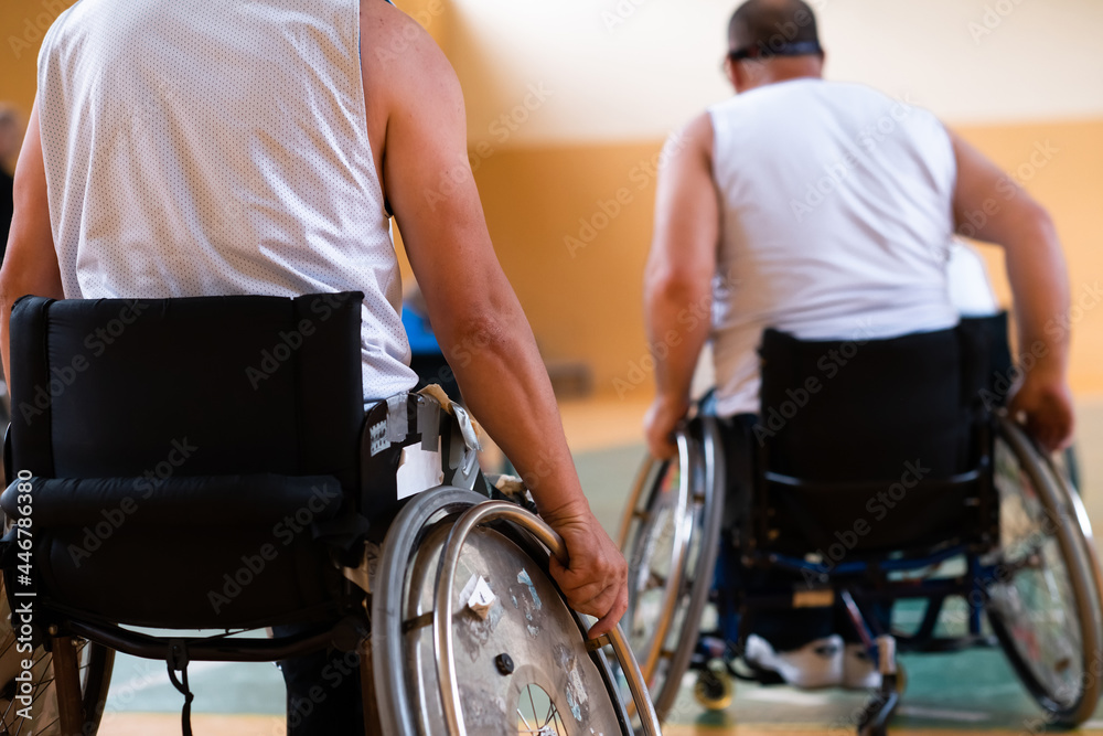 Obraz premium Close up photo of wheelchairs and handicapped war veterans playing basketball on the court