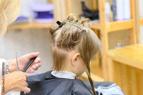 Little girl with dark hair at the hairdresser. Haircut for a child in a beauty salon