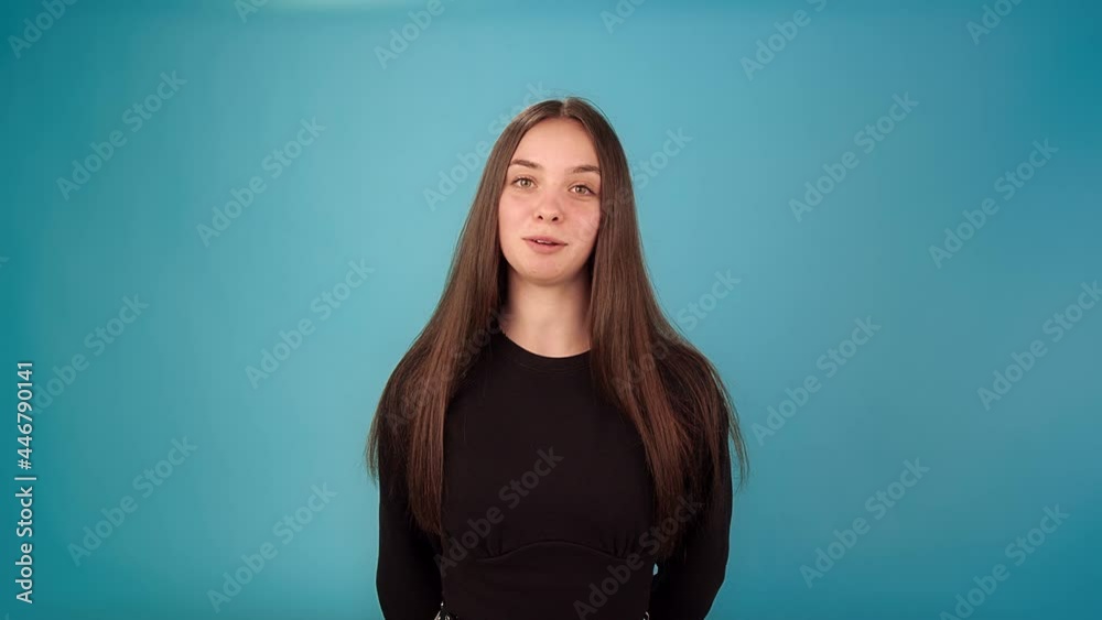 Long haired brunette in black pullover talks looking straight on azure studio background at audition slow motion close view Long haired brunette in black pullover talks looking straight on azure studio background at audition slow motion close view
