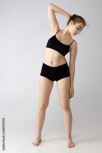 Young beautiful adorable girl in black lingerie posing isolated over gray studio background. Natural beauty concept.
