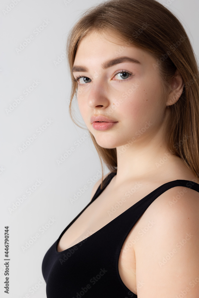 Close-up beautiful adorable young girl in black lingerie posing isolated over gray studio background. Natural beauty, spa, cosmetics and aesthetic cosmetology concept. Close-up beautiful adorable young girl in black lingerie posing isolated over gray studio background. Natural beauty, spa, cosmetics and aesthetic cosmetology concept.