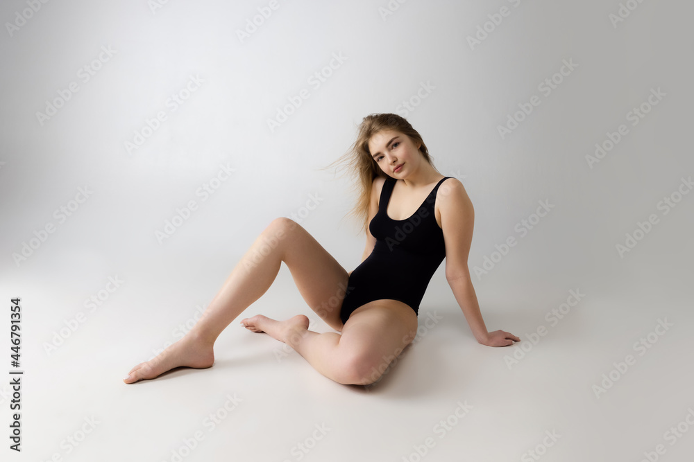 Fototapeta premium Young beautiful adorable girl in black lingerie posing isolated over gray studio background. Natural beauty, spa, cosmetics, fitness and aesthetic cosmetology concept.