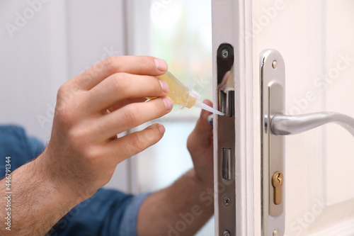 Obraz na płótnie Repairman lubricating door lock at home, closeup