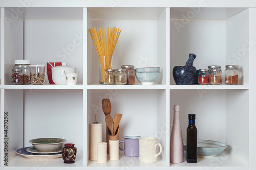 Kitchen utensils and tableware on white shelves. Well organized kitchen concept. Modern interior.