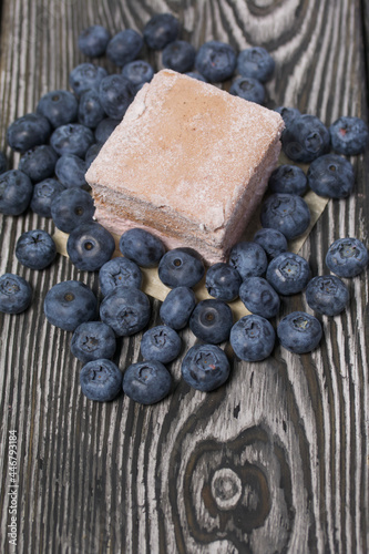 Blueberries are scattered on pine boards. Portion marshmallow. Close-up shot.
