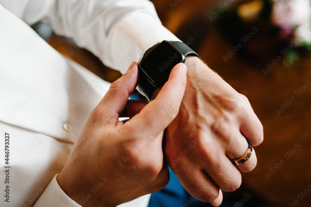 Man in a shirt adjusts the watch on his arm. Close up of businessman using watch.