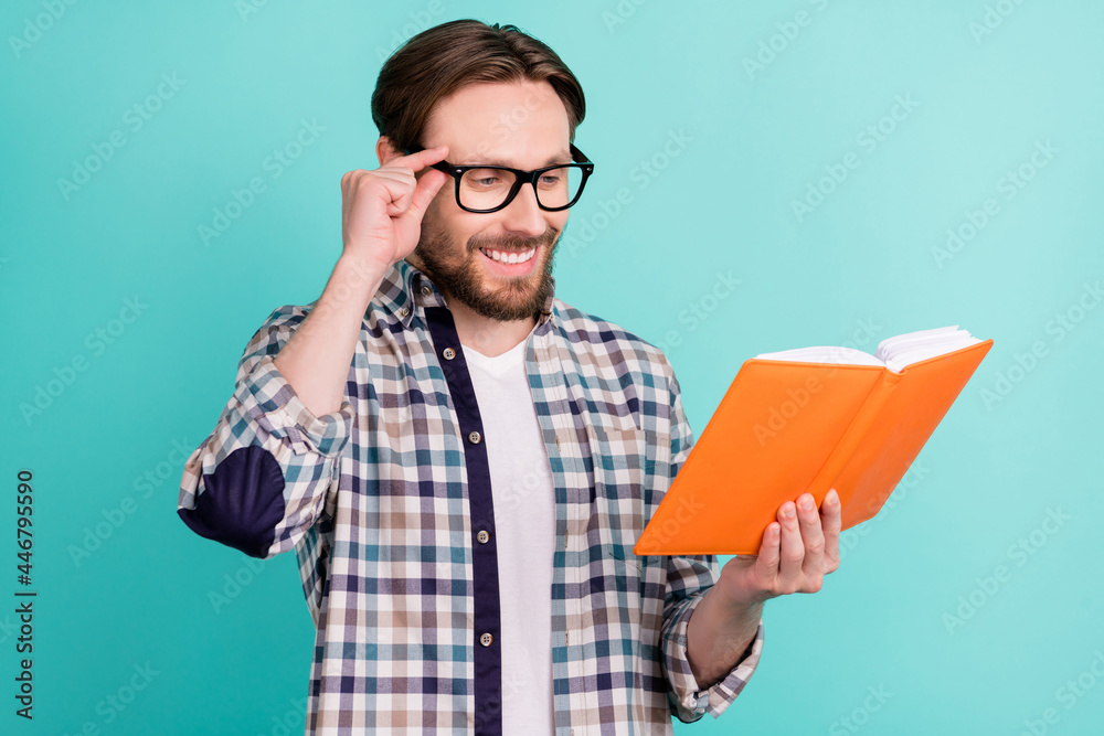Profile side photo of young man happy positive smile read book materials education isolated over teal color background Profile side photo of young man happy positive smile read book materials education isolated over teal color background