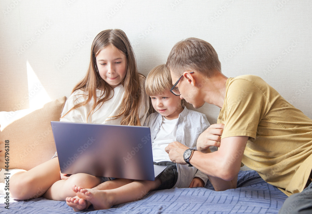 the boy is doing homework on a laptop with his sister and dad. The concept of online learning the boy is doing homework on a laptop with his sister and dad. The concept of online learning