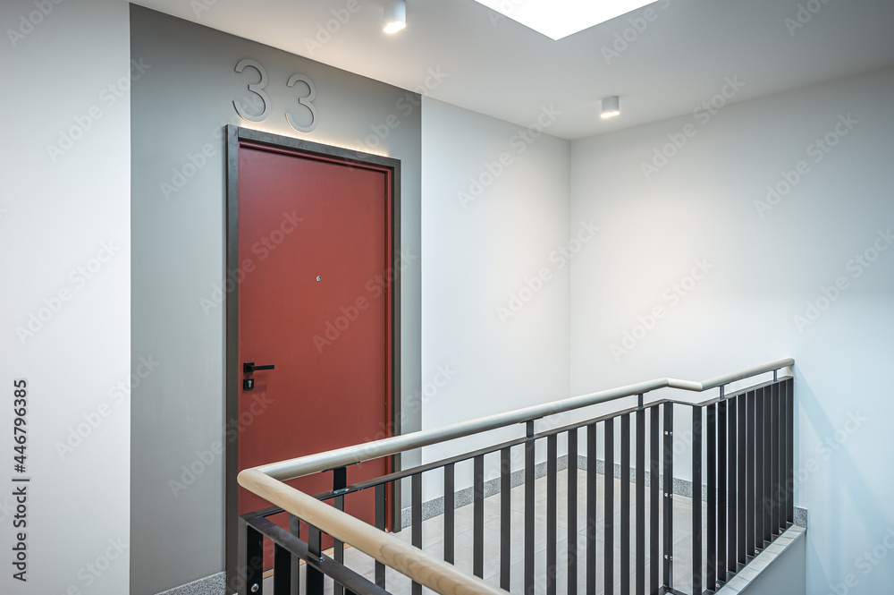 Staircase of modern apartment building. White walls with marble decorations. Metalic railings and tile floor. Clean look.
