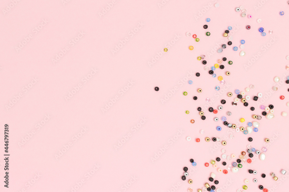 Multicolored beads scattered on a pink background with copyspace. Multicolored beads scattered on a pink background with copyspace.