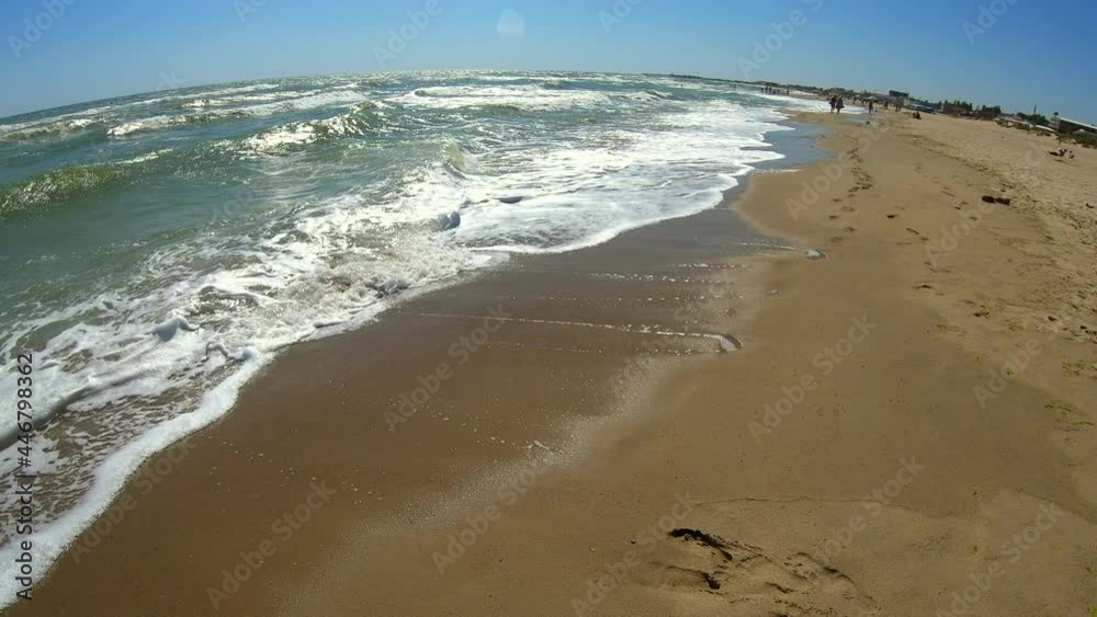 Sea wave with white foam rolls over sandy shore of beach. Top view. Sea wave with white foam rolls over sandy shore of beach. Top view.
