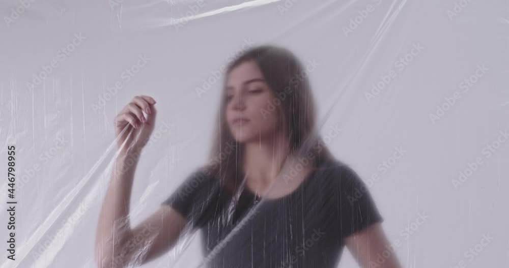Female abuse. Problem escape. Society separation. Defocused confused disturbed woman victim way searching behind clear plastic cover isolated on light out of focus background. Female abuse. Problem escape. Society separation. Defocused confused disturbed woman victim way searching behind clear plastic cover isolated on light out of focus background.