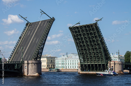 Russian warship sails under an open palace bridge along the Neva River in St. Petersburg during a festive parade on a sunny summer day