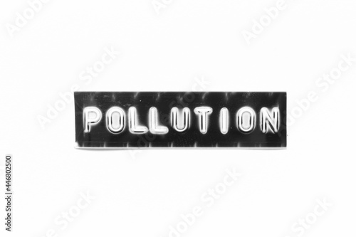 Embossed letter with word pollution in black banner on white paper background