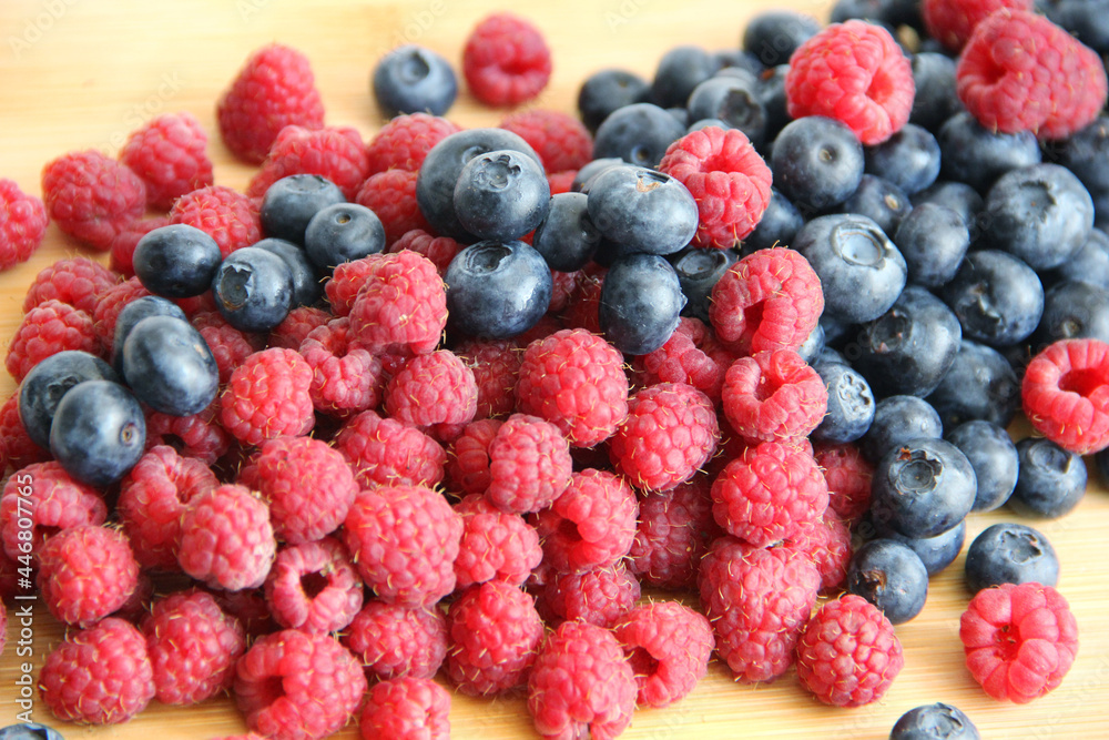 raspberries and blueberries on wooden table raspberries and blueberries on wooden table