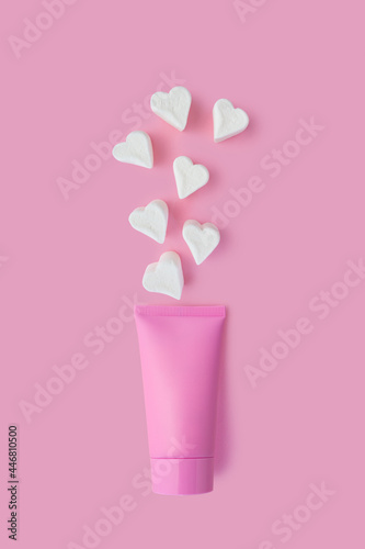 Creative beauty fashion concept photo of cosmetic recyclable bottle lotion cream with marshmallow candy on pink background.