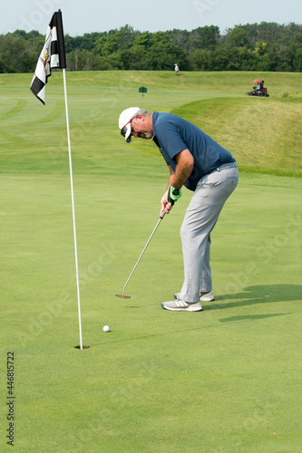 A golfer putting watches his putt approach the hole.