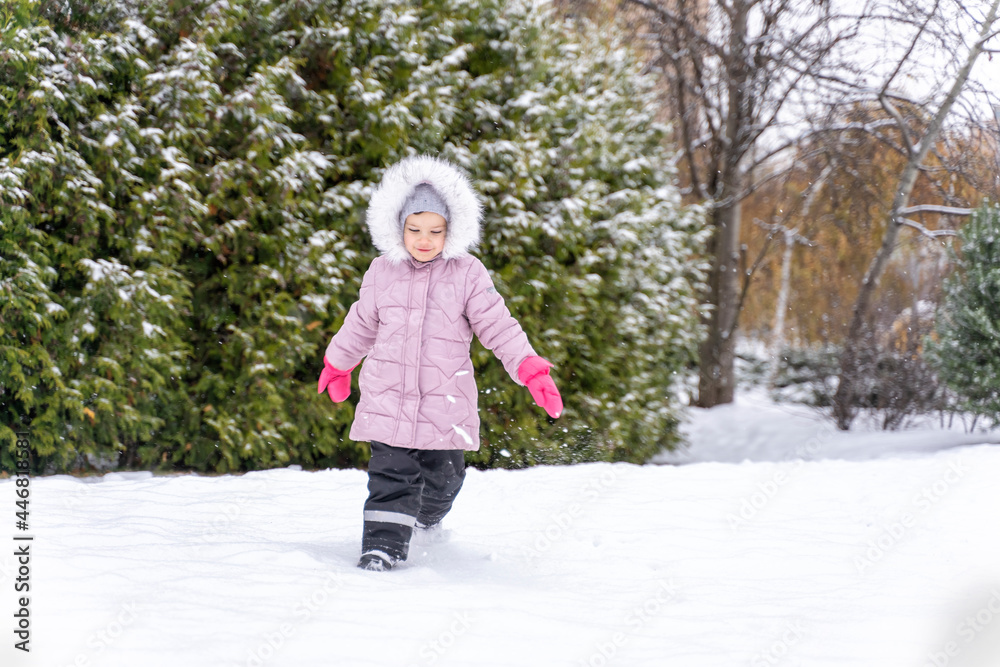 happy little girl girl in pink coat having fun in winter park and playing with snow happy little girl girl in pink coat having fun in winter park and playing with snow