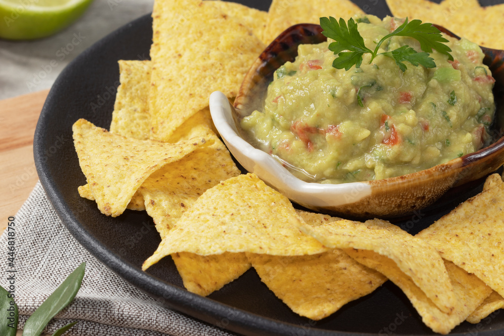 Mexican food, traditional guacamole and nacho on black plate. Mexican food, traditional guacamole and nacho on black plate.