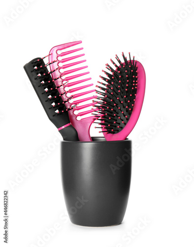 Hairbrushes and comb in holder on white background