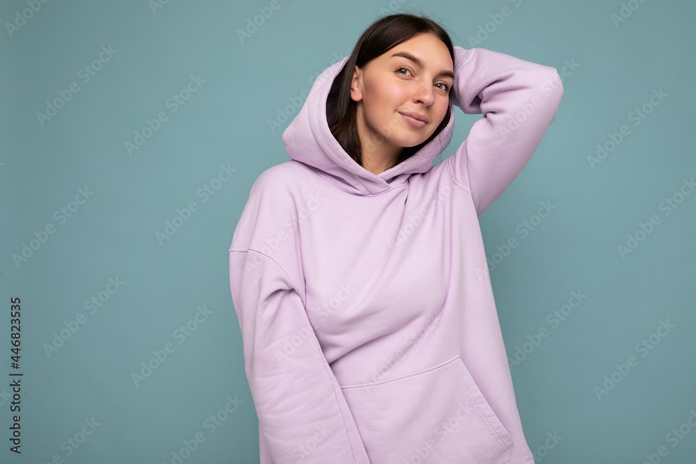 Young cool happy pretty brunet woman with sincere emotions isolated on background wall with copy space wearing casual purple hoodie. Positive concept