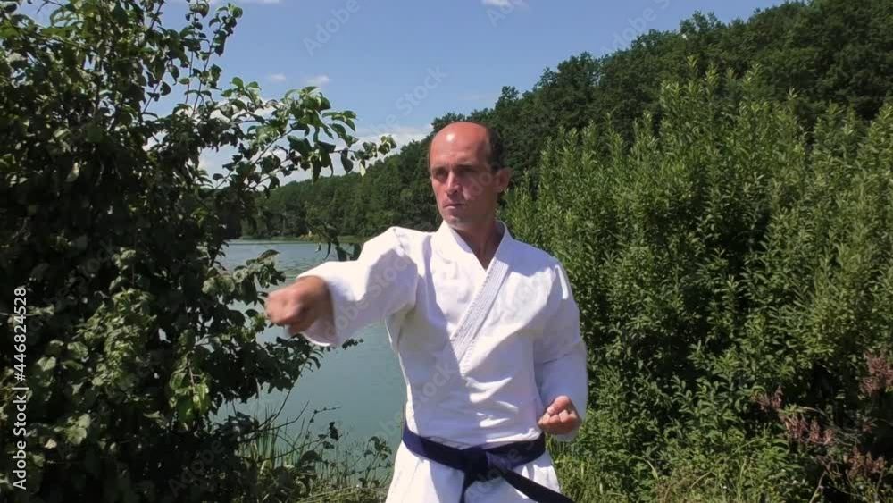 An athlete trains blocks and punches against the backdrop of a pond An athlete trains blocks and punches against the backdrop of a pond