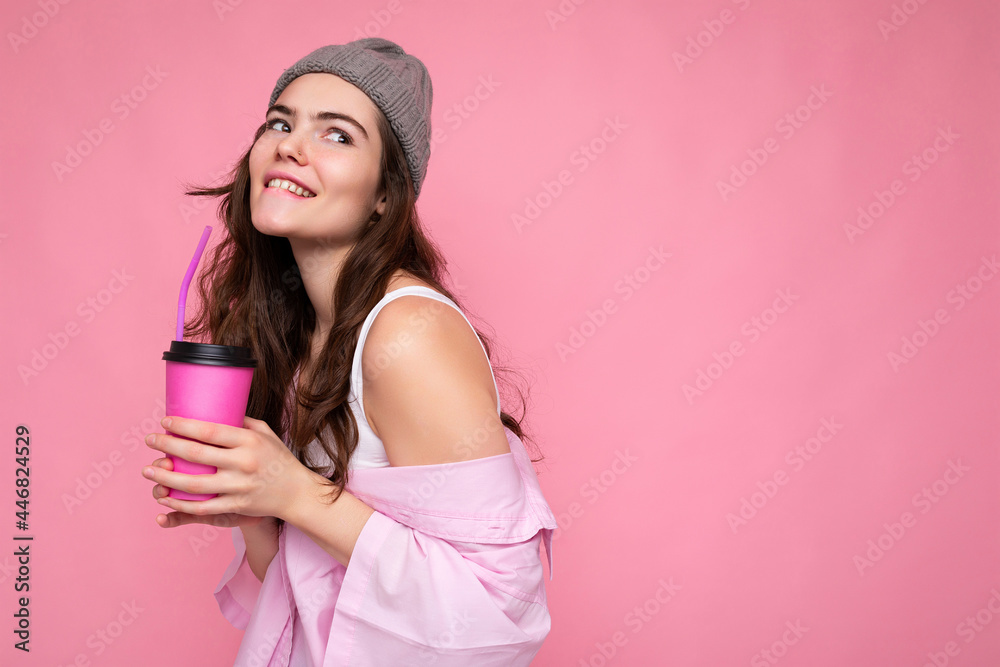 Charming sexy young happy funny brunette woman wearing stylish clothes isolated over colourful background wall holding paper cup for mockup drinking milkshake looking to the side Charming sexy young happy funny brunette woman wearing stylish clothes isolated over colourful background wall holding paper cup for mockup drinking milkshake looking to the side