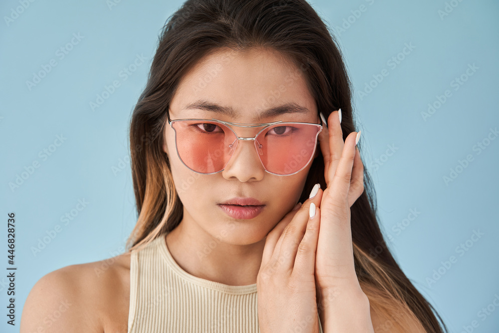 Woman wearing pink sunglasses looking at the camera with serious emotions Woman wearing pink sunglasses looking at the camera with serious emotions