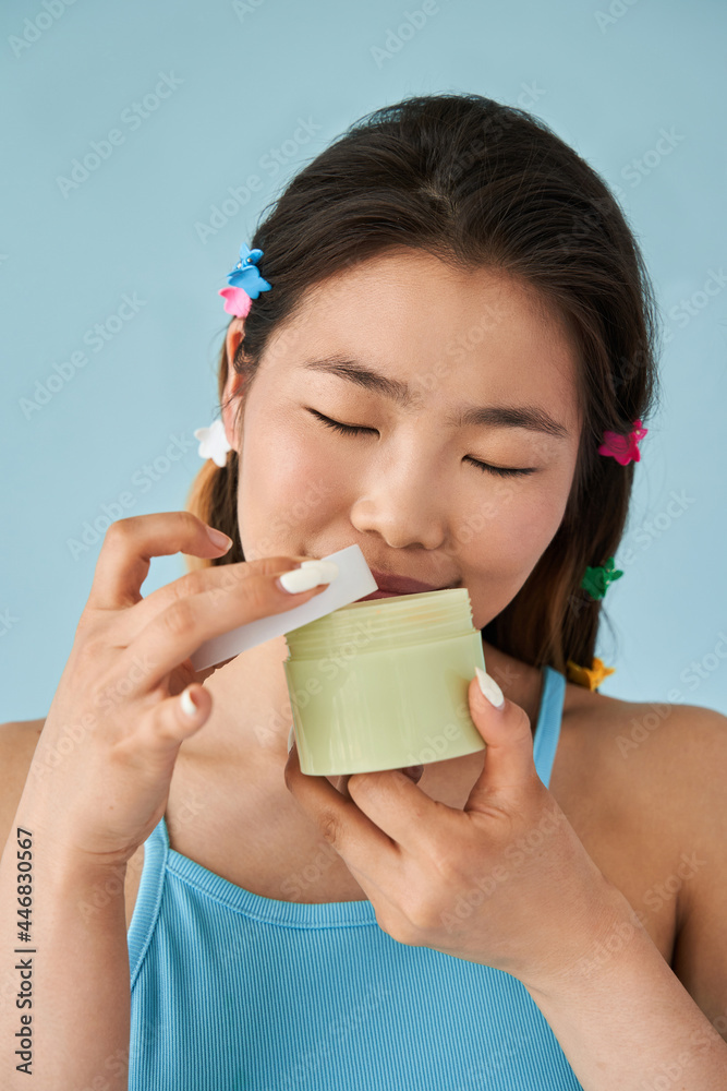 Asian woman smells moisturizer with closed eyes while standing at the studio Asian woman smells moisturizer with closed eyes while standing at the studio